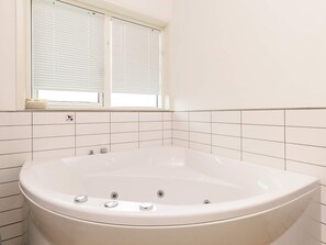 A bathroom with a freestanding bathtub, a window with blinds, and a no-smoking sign.