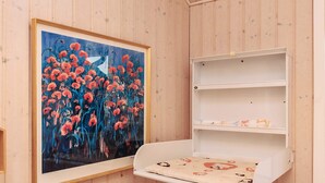A room with wooden paneling, a framed painting of red flowers, and a white shelf unit with a cushion. - 5 Star Holiday Home in Faaborg (Faaborg)