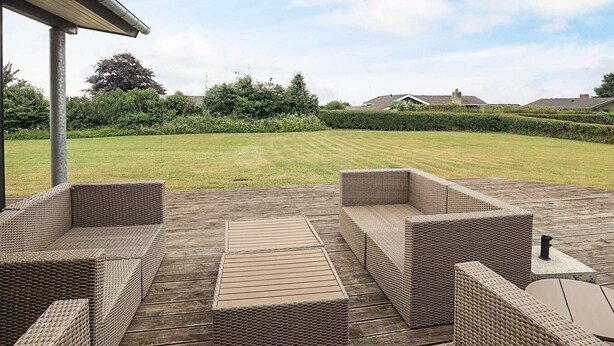 A covered outdoor seating area with wicker furniture and a wooden deck. - 5 Star Holiday Home in Faaborg (Faaborg)