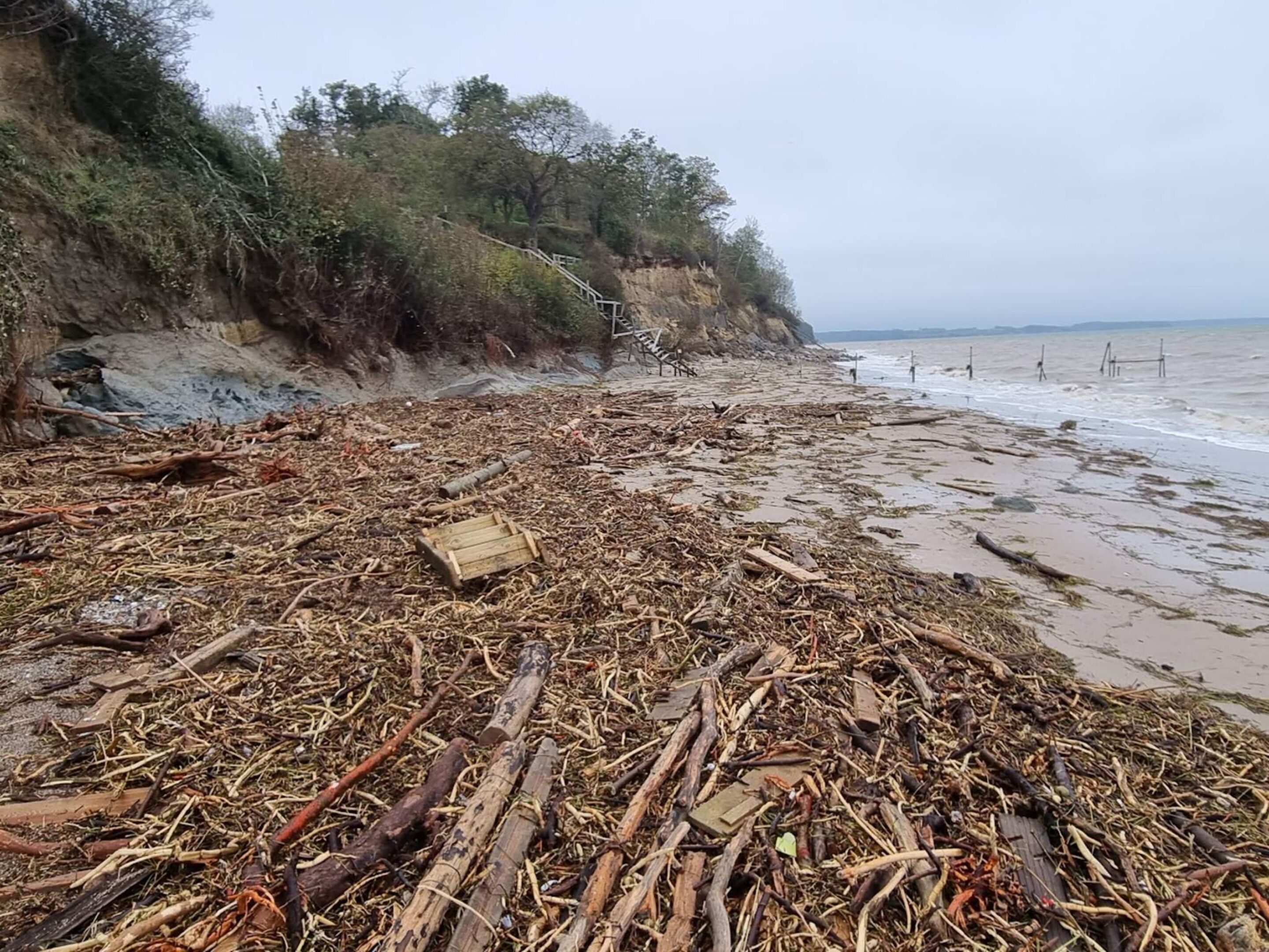 A beach with debris and a wooden structure on the shore.
