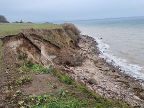 Een kustlandschap met een klif, rotsachtige kustlijn en uitzicht op zee.