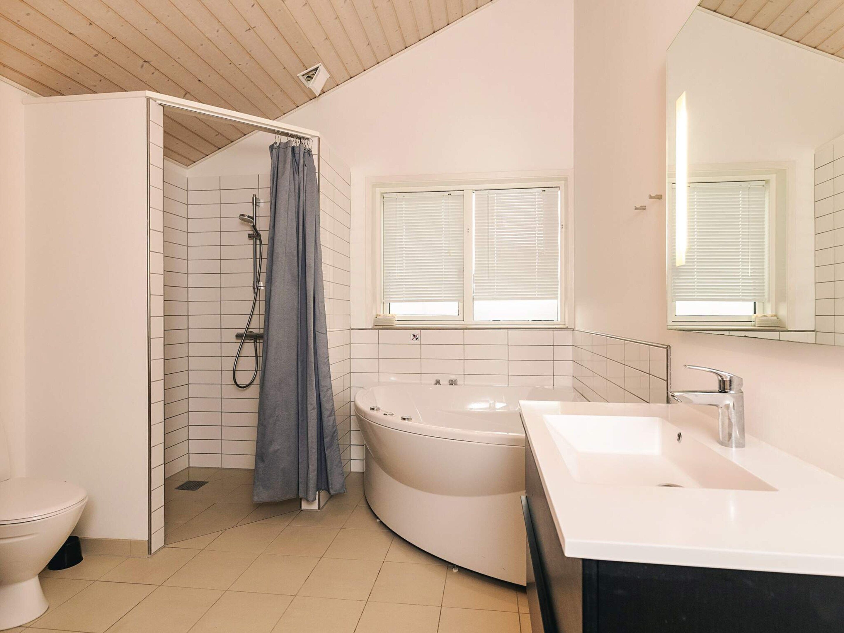 A modern bathroom with a shower, toilet, bathtub, and sink.