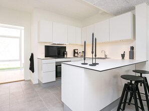 A modern kitchen with white cabinetry, a large island, and a black countertop. - Spacious Apartment in RingkÃ¸bing near Sea (Ringkobing)