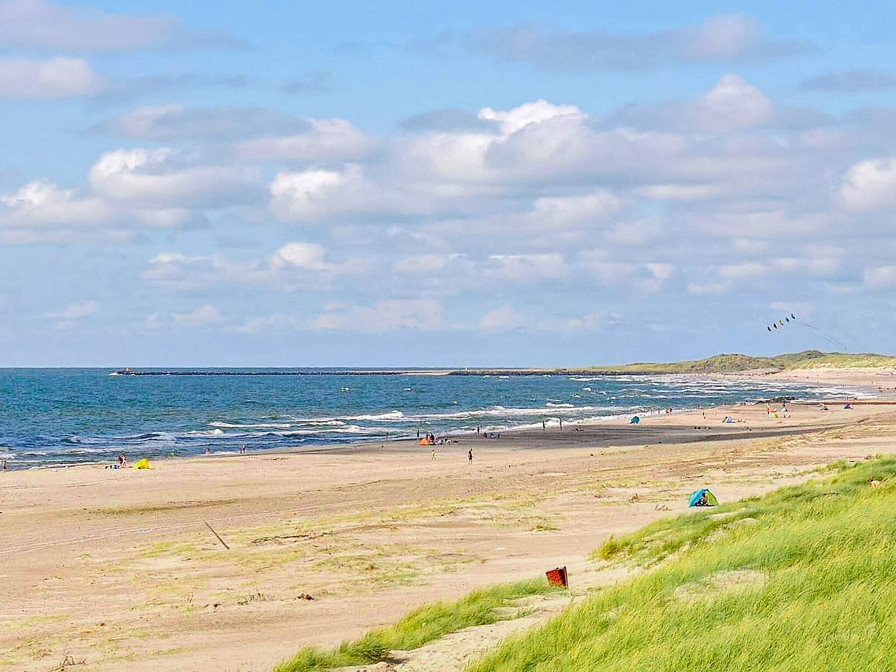 En strand med klart skys og bølger, samt en fjern kystlinje.