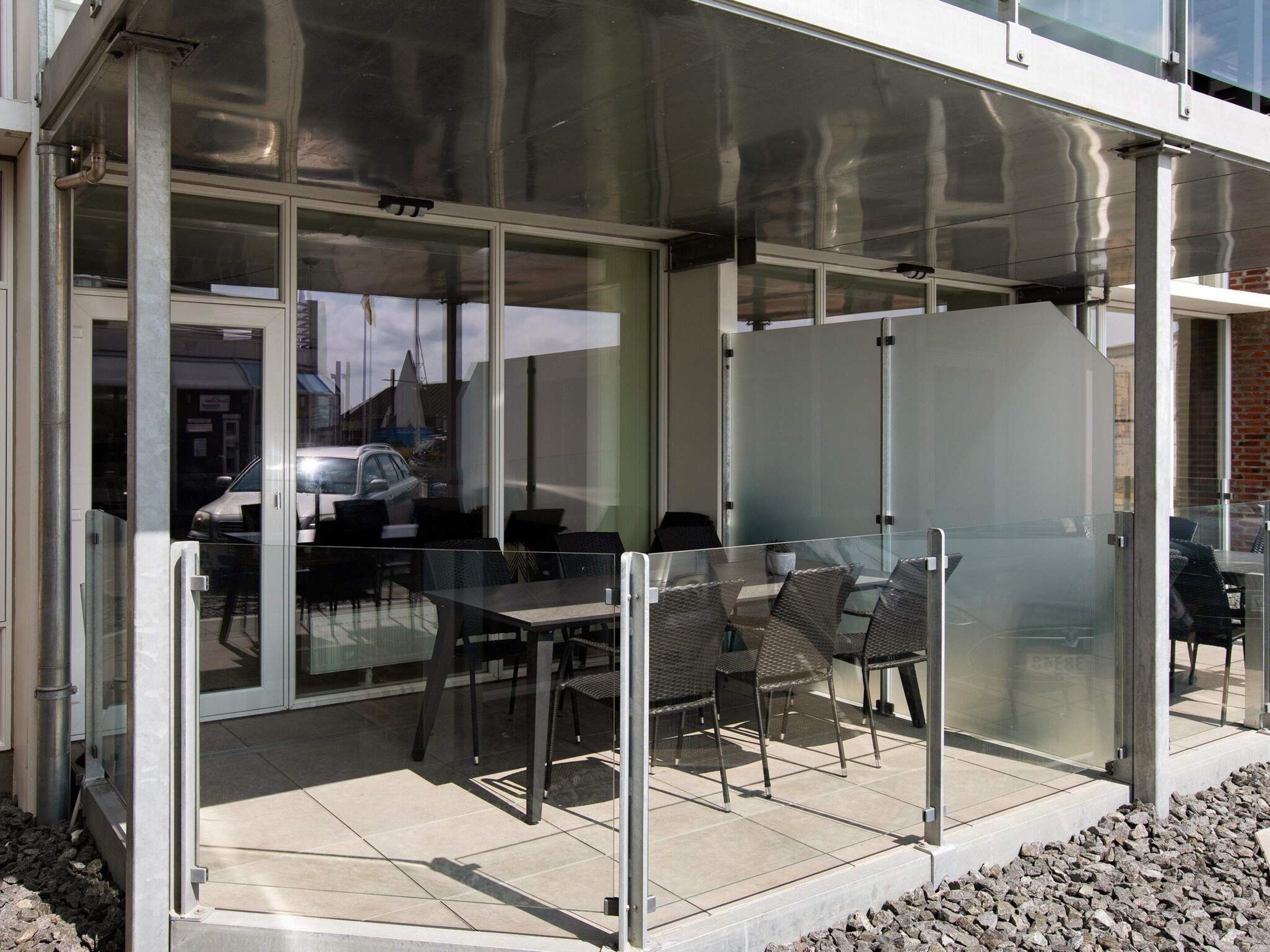 A modern outdoor seating area with glass partitions and metal furniture.