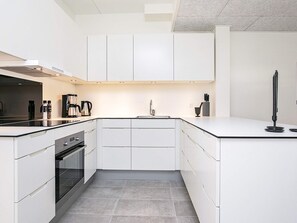 A modern kitchen with white cabinetry, a built-in oven, a coffee maker, and a sink.