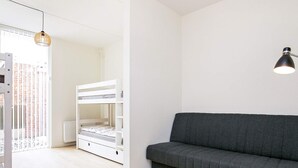 A room with a bunk bed, a grey sofa, a small round table, and a pendant light. - Spacious Apartment in RingkÃ¸bing near Sea (Ringkobing)