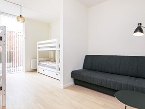 A room with a bunk bed, a grey sofa, a small round table, and a pendant light. - Spacious Apartment in RingkÃ¸bing near Sea (Ringkobing)