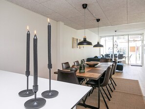 A modern dining area with a long table, black candle holders, and pendant lighting.
