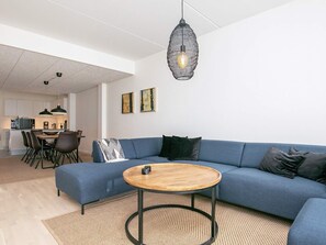 A modern living room with a blue sofa, a wooden coffee table, and a hanging light fixture. - Spacious Apartment in RingkÃ¸bing near Sea (Ringkobing)