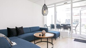 A modern living room with a sectional sofa, a round coffee table, and a hanging light fixture. - Spacious Apartment in RingkÃ¸bing near Sea (Ringkobing)