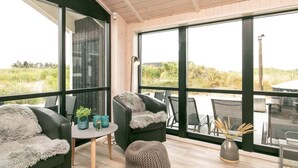 Een modern interieur met grote ramen, een ronde tafel, twee stoelen en een klein voetenbankje.