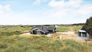 Een huis met een ruime veranda, een schommel en een omheind speelveld in een grasveld.