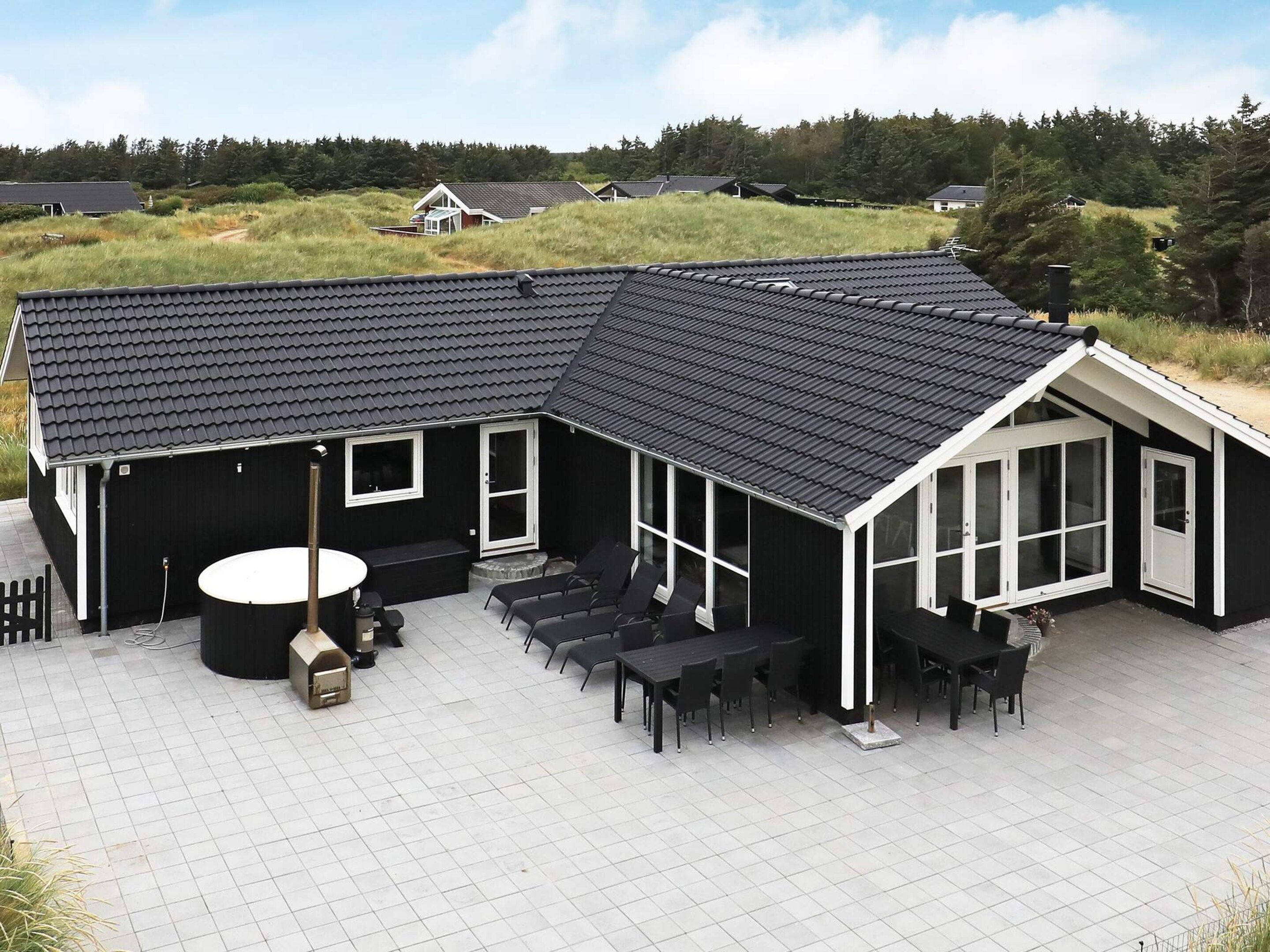 A black building with a tiled roof and a patio area with outdoor furniture.