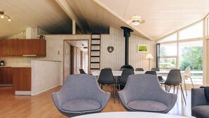 Een moderne keuken met houten kastjes en een eethoek met grijs gestoffeerde stoelen en een witte tafel.