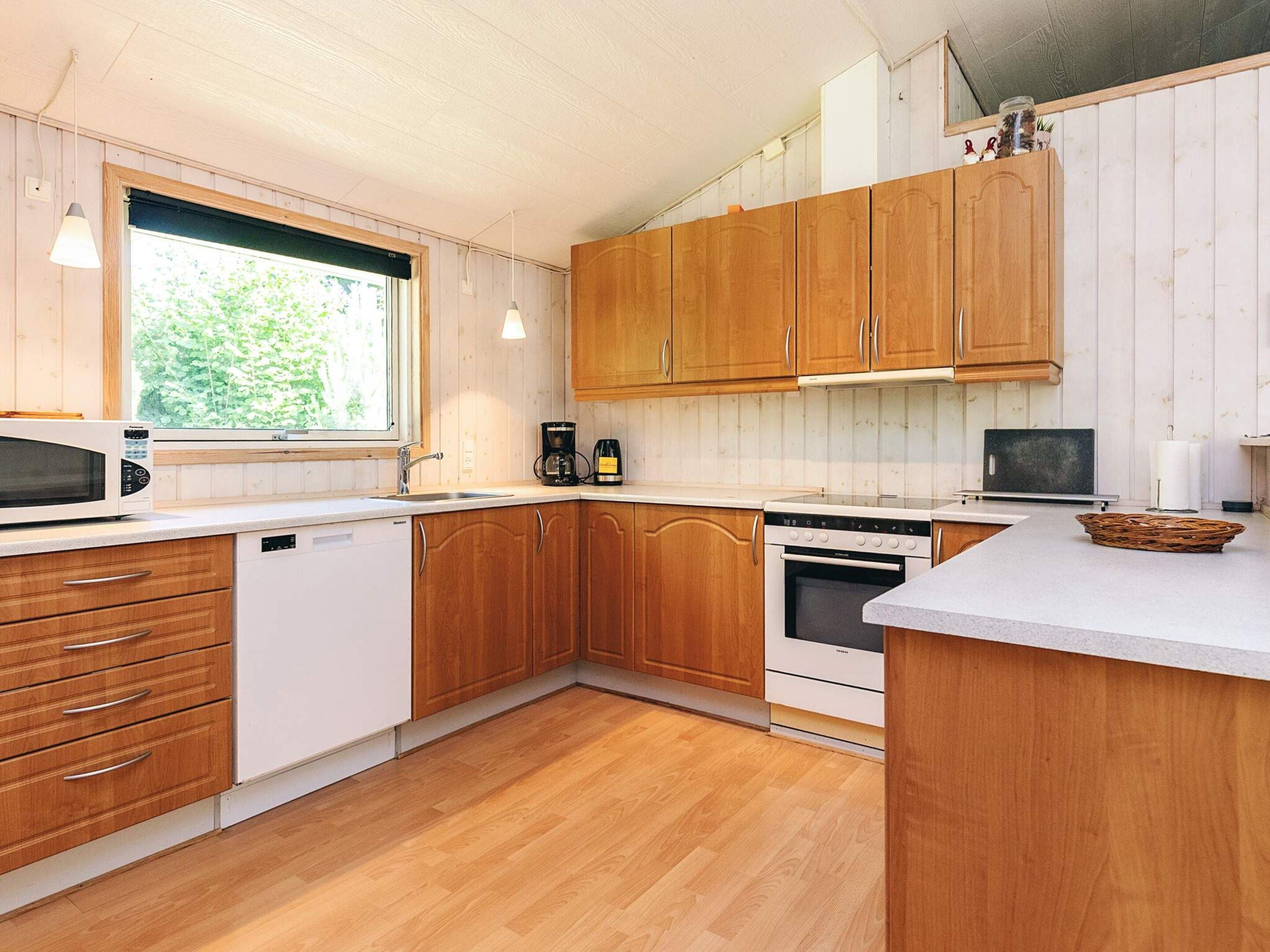 A modern kitchen with wooden cabinets, a built-in oven, a microwave, and a coffee maker.