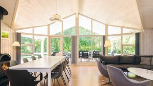 Een modern interieur met een lange eettafel, stoelen, een bank en een open haard.