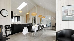 A modern interior with a dining area, kitchen, and a black leather sofa. - 5 Star Holiday Home in Blavand (Blavand)