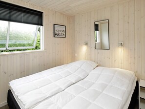 A bedroom with a bed, a window with blinds, a framed picture, and a wall-mounted mirror. - 5 Star Holiday Home in Blavand (Blavand)