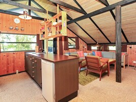 Un interior rústico con techo de madera, una kitchenette, un comedor con mesa y sillas, y un sofá.