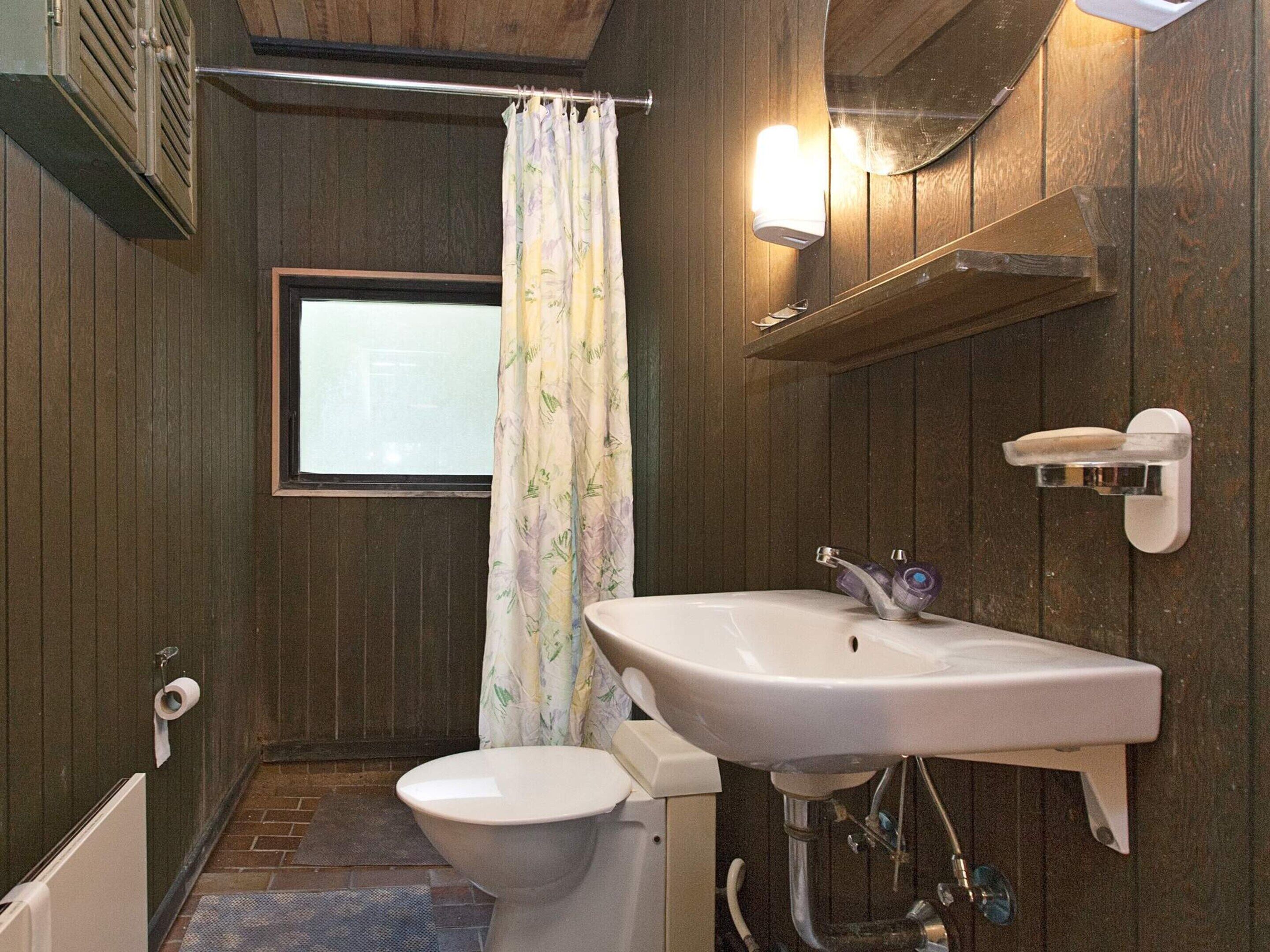 A small bathroom with a toilet, a sink, and a shower curtain.