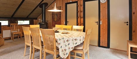 Un rincón comedor acogedor con una mesa y sillas de madera, una lámpara colgante y un estufa de leña.