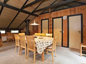 A cozy dining area with a wooden table and chairs, a hanging light fixture, and a wood-burning stove.