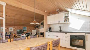 Uma cozinha moderna com armários brancos, uma mesa de jantar de madeira e um forno embutido.