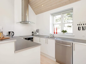 A modern kitchen with a central island, stainless steel appliances, and a window with a view.