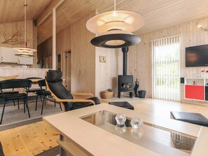 A modern interior with a wooden ceiling, a fireplace, a dining area, and a TV. - 5 Star Holiday Home in Vaeggerlose (Vaeggerlose)
