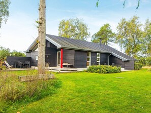 A modern house with a sloped roof, a visible chimney, and a well-maintained lawn. - 5 Star Holiday Home in Glesborg (Glesborg)