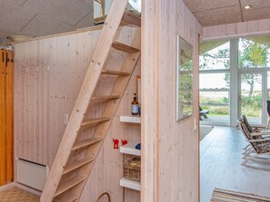 A wooden interior with a spiral staircase, a wooden cabinet, and a view of the outdoors. - 5 Star Holiday Home in Glesborg (Glesborg)