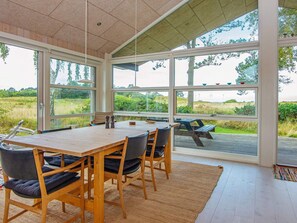 A dining area with a large table and chairs, large windows offering a view of the outdoors. - 5 Star Holiday Home in Glesborg (Glesborg)