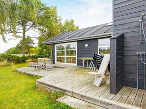A modern house with a deck, outdoor furniture, and a large window.
