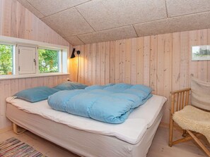 A bedroom with a bed, a window, a lamp, and a chair.