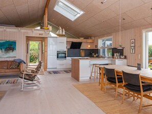 A modern kitchen with a central island, wooden cabinets, and a dining area with a table and chairs. - 5 Star Holiday Home in Glesborg (Glesborg)