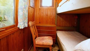 Une chambre dans un chalet en bois, avec un lit superposé, un bureau et une chaise.