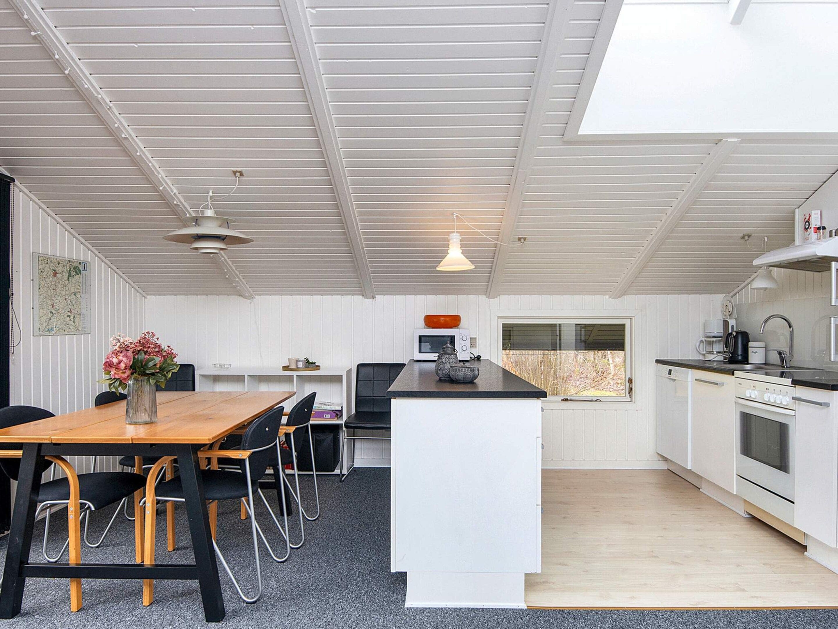 A modern kitchen with white cabinetry, a wooden dining table, and a central island.