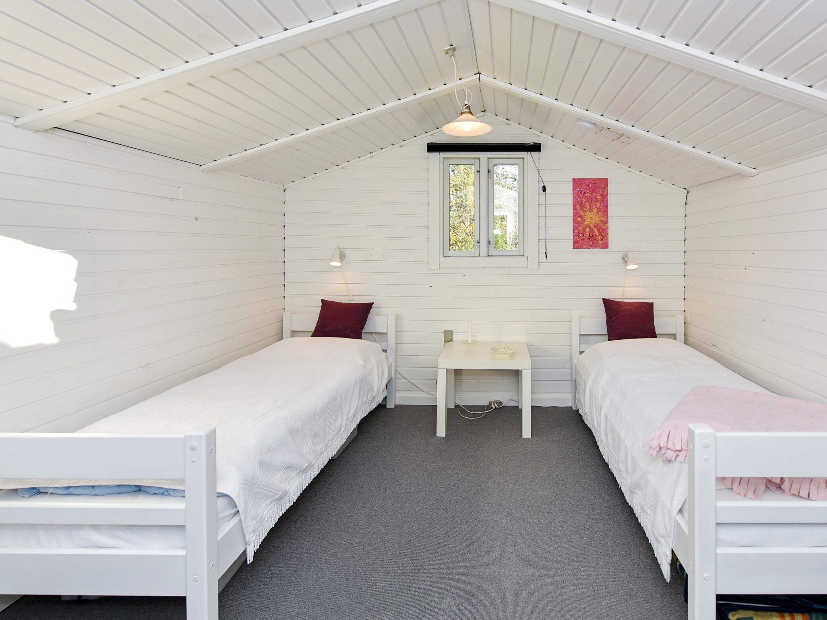 Une chambre avec deux lits simples, une petite table et une fenêtre.
