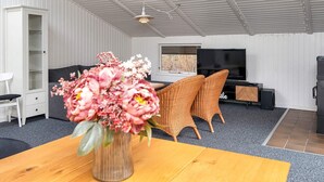 A modern living room with a wooden coffee table, a sofa, wicker chairs, a TV, and a white wardrobe. - 4 Star Holiday Home in Ansager (Ansager)