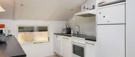 A modern kitchen with white cabinetry, a built-in oven, a refrigerator, and a window providing a view of the outdoors.