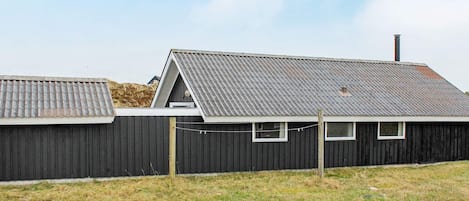A building with a corrugated metal roof, a wooden fence, and a gravel driveway.