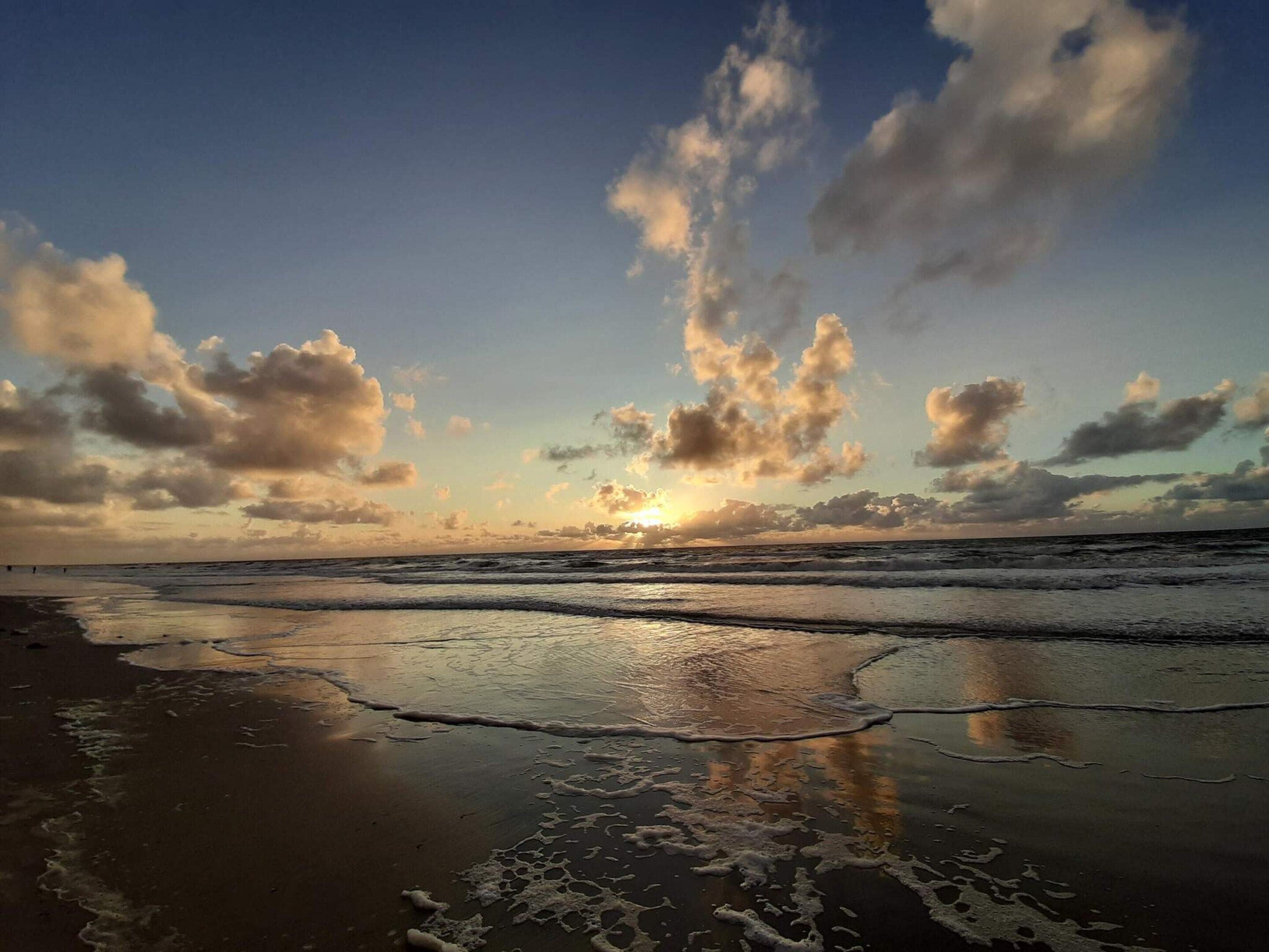 A beach with waves and a sunset.