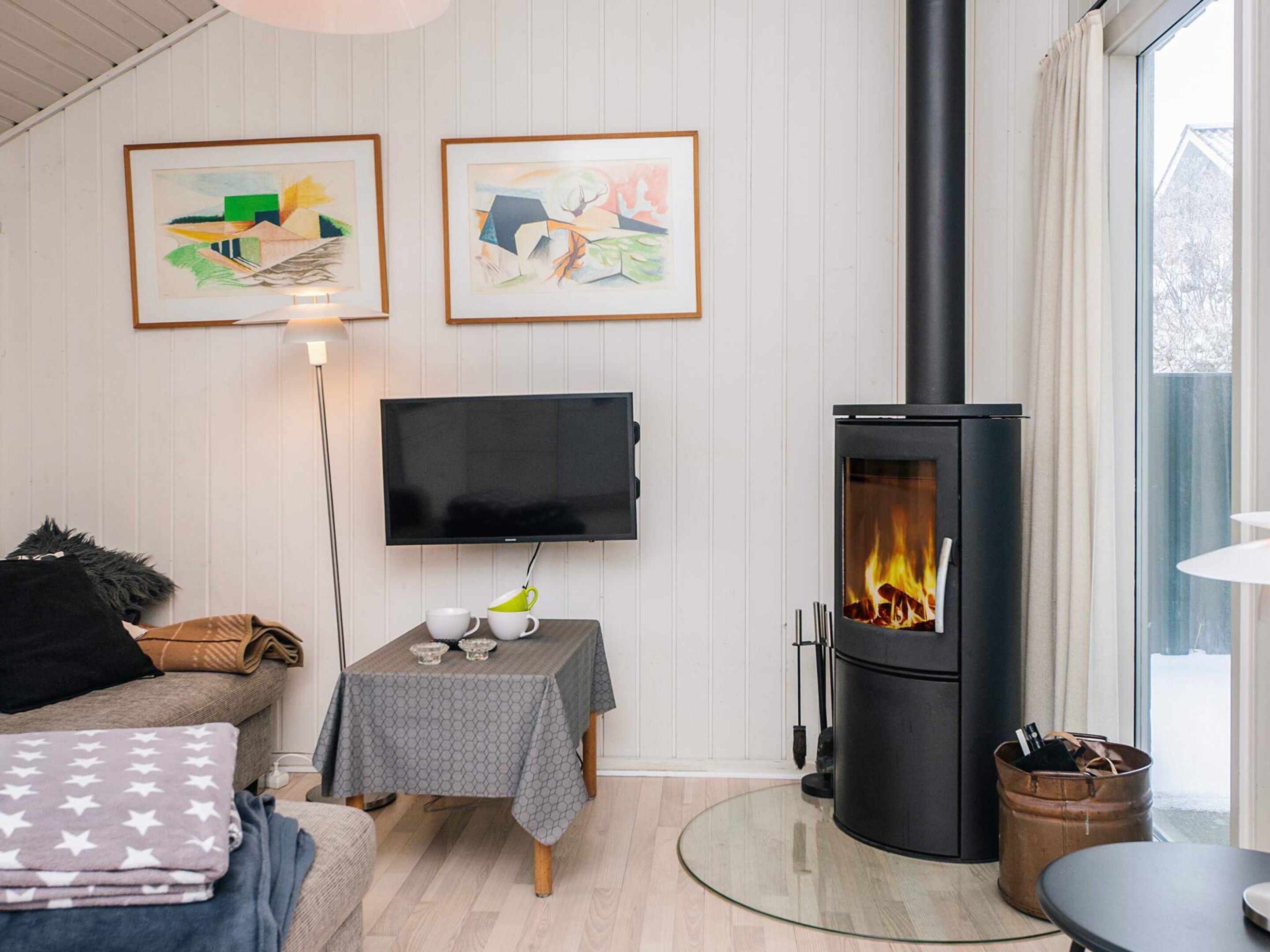 Una sala de estar con chimenea, un televisor de pantalla plana y dos obras de arte enmarcadas en la pared.