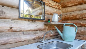 A rustic wooden cabin interior with a metal sink, a mirror, and a green watering can on a shelf. - Serene Holiday Home in Lemvig near Sea (Lemvig)