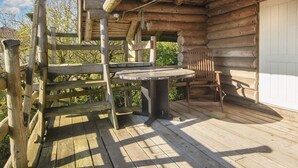 A wooden cabin with a deck, a table, and a chair. - Serene Holiday Home in Lemvig near Sea (Lemvig)