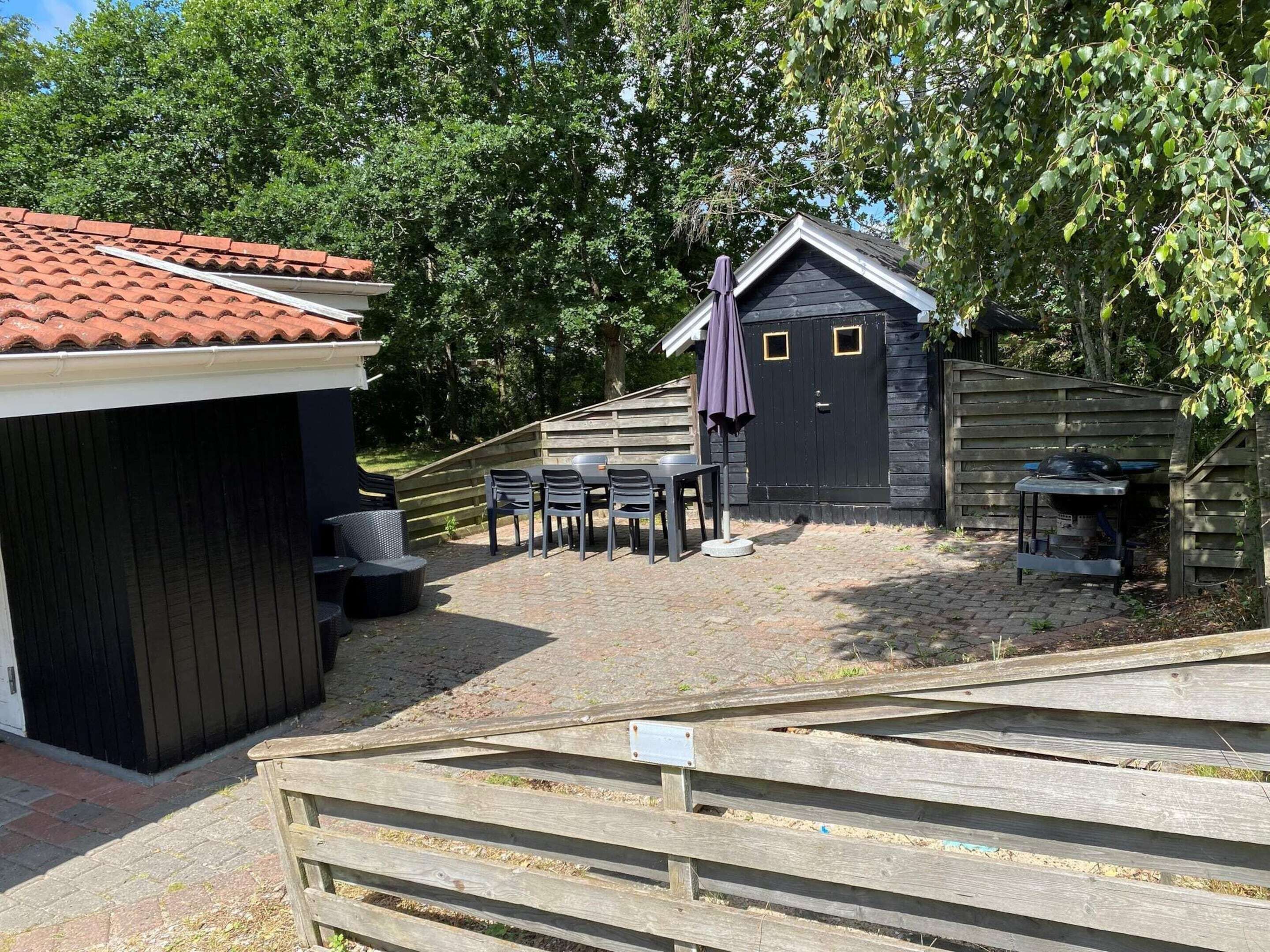 A patio area with outdoor seating, a barbecue grill, and a small shed.