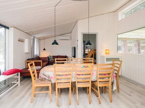 A cozy room with a dining table surrounded by chairs, a sofa, and a bunk bed in the background. - 7 Person Holiday Home in Orsted (Ørsted)