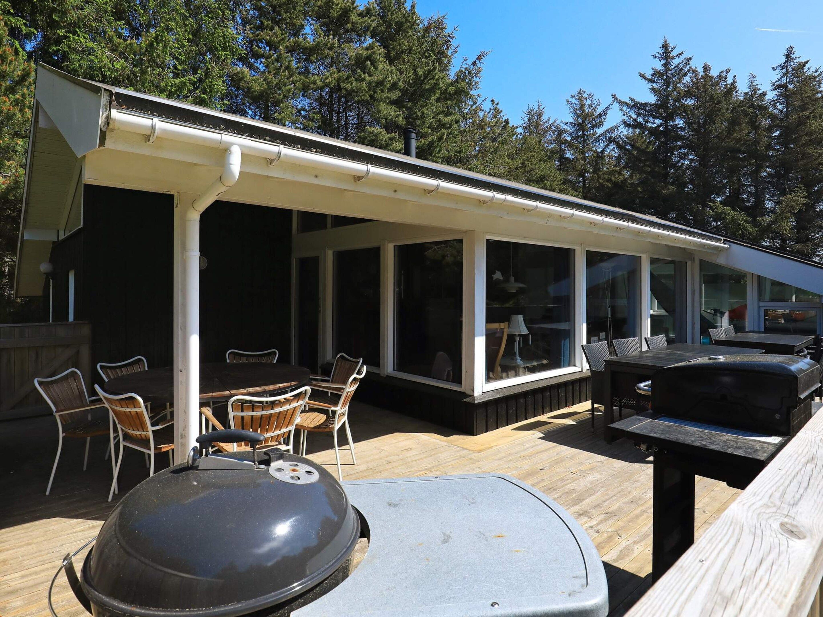 An outdoor patio with a grill, dining table, and chairs.