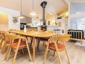 Un espace de salle à manger moderne avec une table ronde en bois entourée de chaises, une cheminée et des luminaires suspendus.